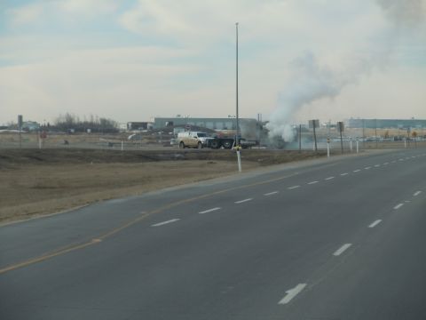 2009 Kenworth T800 - A truck is seen emitting a large plume of smoke on the side of a highway, with another vehicle nearby.