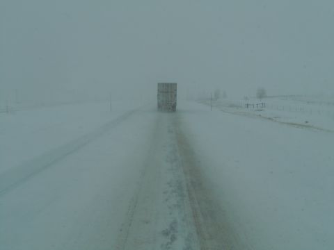 2009 Kenworth T800 - A truck drives down a highway during a snowstorm, with limited visibility.