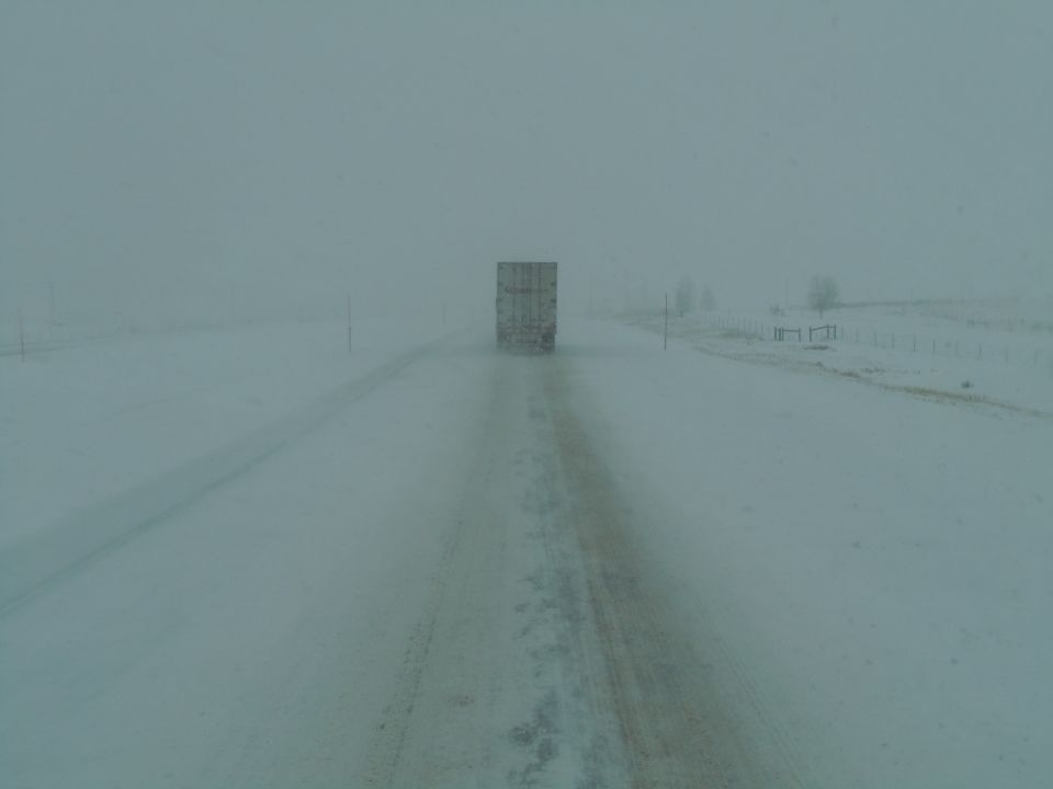 Truck trailer on a snow-covered road in a blizzard
