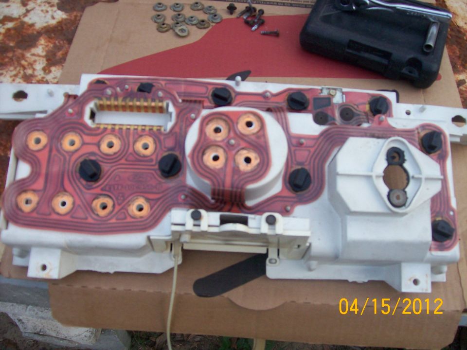 Back of a vehicle's instrument cluster circuit board with copper traces and black connectors