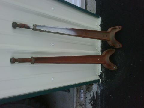 1996 Ford Bronco - Two rusty metal suspension components are shown leaning against a white corrugated wall.