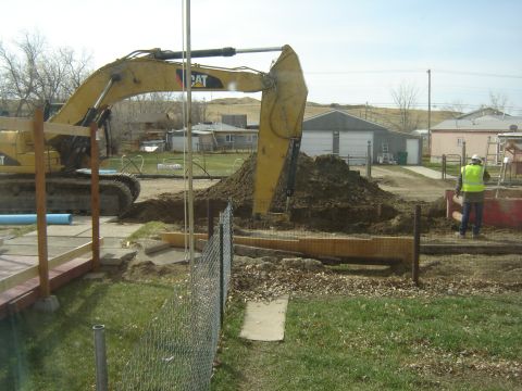 1984 Ford Mustang - Construction work is underway as an excavator digs a large hole, creating a mound of soil.
