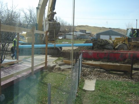 1984 Ford Mustang - Construction equipment is actively working at a site, moving dirt and a large blue pipe.