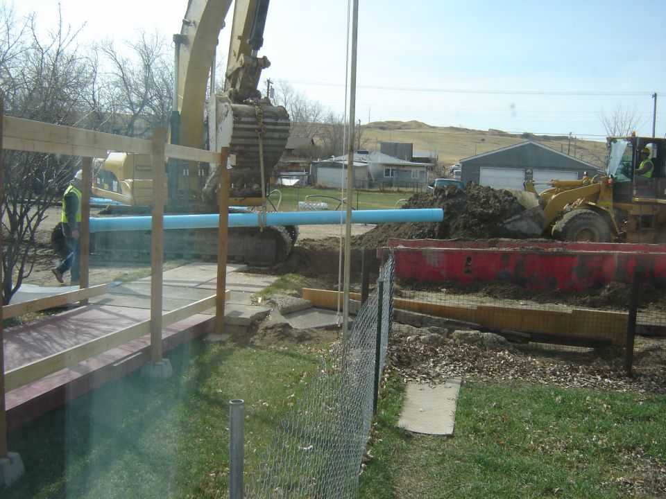 Yellow excavator and front loader moving dirt and pipe at a construction site