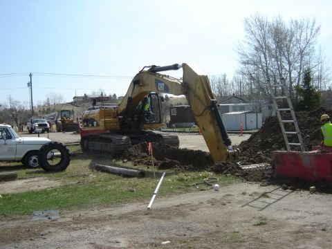 1984 Ford Mustang - Construction scene with an excavator digging a trench, a white pickup truck, and a ladder leaning against a pile of dirt.