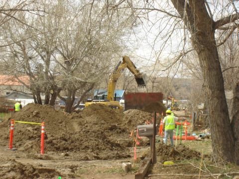1984 Ford Mustang - Construction work is underway with an excavator moving dirt and workers overseeing the project.