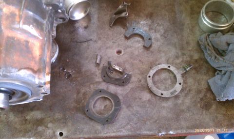 1987 Ford Bronco - Various metal components, possibly from a vehicle transmission, are disassembled on a rough surface.