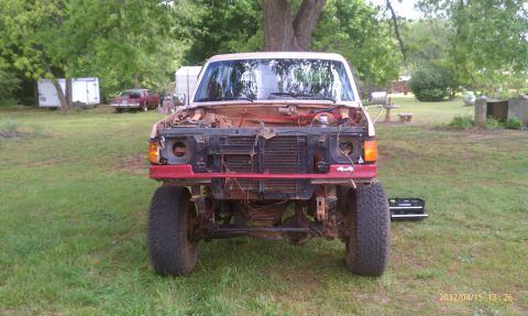 1987 Ford Bronco - This truck is missing its grille and hood, with the engine bay exposed. A '4x4' badge is visible on the front bumper.