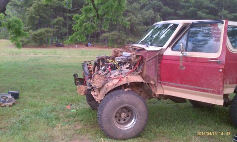 1987 Ford Bronco - This 1987 Ford Bronco is undergoing repairs outdoors, with its engine compartment open and parts laid out nearby.