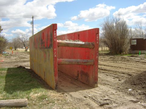 1984 Ford Mustang - A red trench box is positioned on a dirt construction site under a cloudy sky.