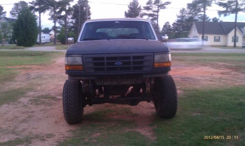 1987 Ford Bronco - Lifted Ford Bronco with a prominent grille and off-road tires, viewed from the front.