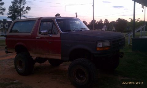 1987 Ford Bronco - This lifted Ford Bronco has a two-tone paint scheme with a red rear and a dark gray front.