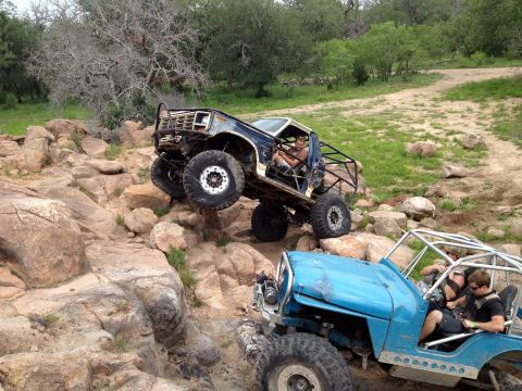 1986 Ford Bronco - Two modified off-road vehicles tackle a challenging rocky trail with steep inclines.