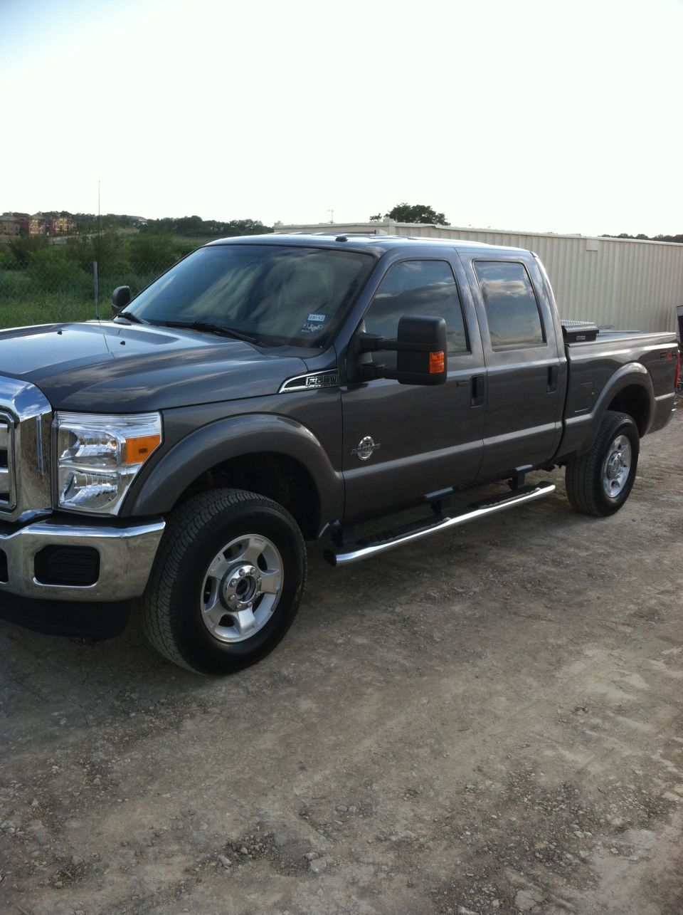 Dark gray crew cab pickup truck parked on a dirt lot