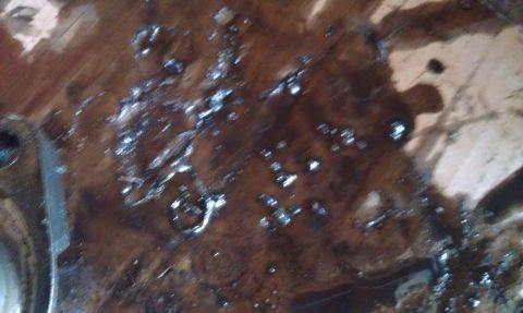 1978 Ford Bronco - Engine oil and metal fragments are visible on a surface, suggesting mechanical wear or a leak.