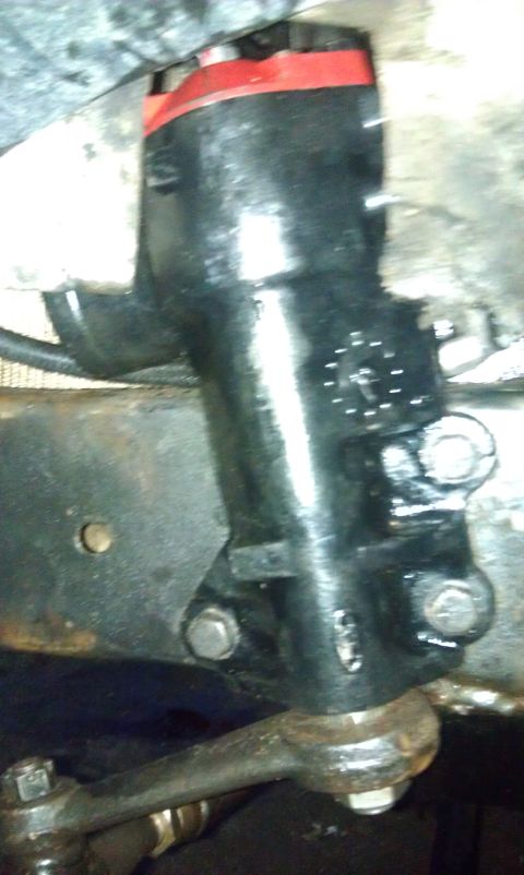 1978 Ford Bronco - Close-up of a vehicle's steering mechanism, showing a black component with a red top and linkage.
