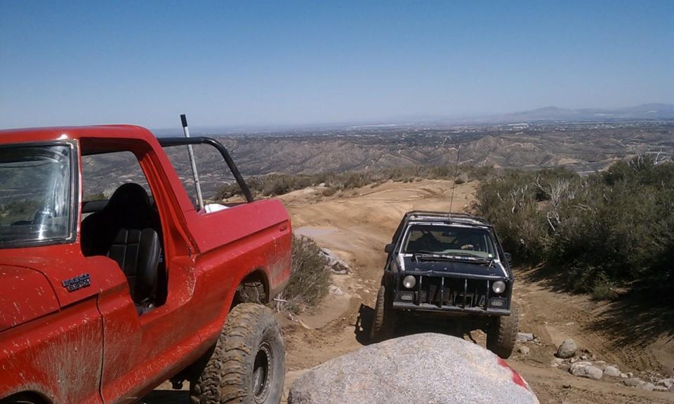 Red 1978 Ford Bronco and black SUV on a mountain trail