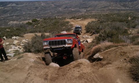 1978 Ford Bronco - A red 1978 Ford Bronco navigates a challenging rocky terrain, with another SUV following behind.