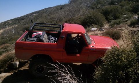 1978 Ford Bronco - This red 1978 Ford Bronco is navigating a steep, rocky incline on a sunny day.
