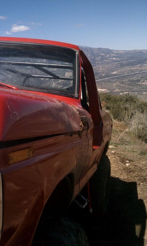 1978 Ford Bronco - This red SUV is parked on a hillside with a scenic view of the valley below.