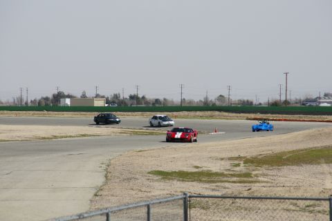 1995 Ford Taurus - Multiple vehicles compete on a race track under a hazy sky.
