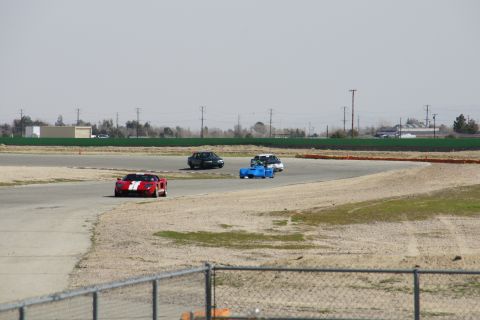 1995 Ford Taurus - Multiple vehicles on a race track during a sunny day.