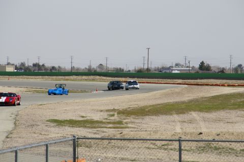 1995 Ford Taurus - Multiple vehicles are seen on a race track under a hazy sky.