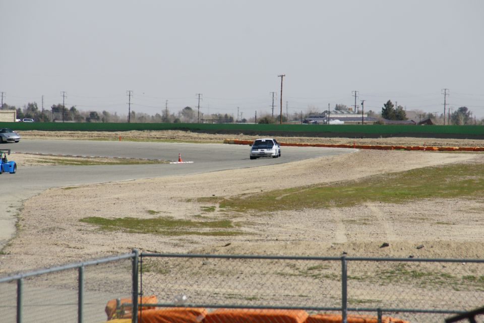 1995 Ford Taurus on a race track, with a blue go-kart in the background