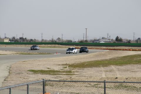 1995 Ford Taurus - Cars race on a track under a hazy sky.