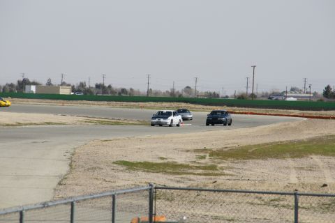 1995 Ford Taurus - Multiple cars are seen on a racetrack during a sunny day.