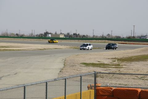 1995 Ford Taurus - Multiple vehicles are seen on a race track under a hazy sky.
