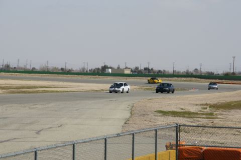 1995 Ford Taurus - Several cars are seen on a race track during a sunny day, with a white car with a black hood in the foreground.