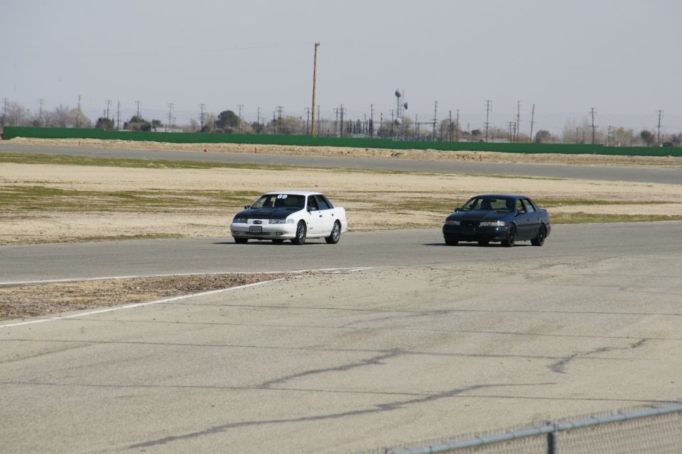 1995 Ford Taurus and a dark sedan on a race track, both facing forward