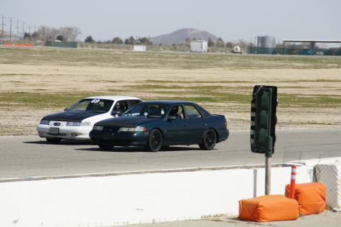 1995 Ford Taurus - Two sedans compete on a race track, with one displaying the number 69.