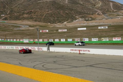 1995 Ford Taurus - Multiple vehicles race on a track with a mountain backdrop and numerous sponsor signs.