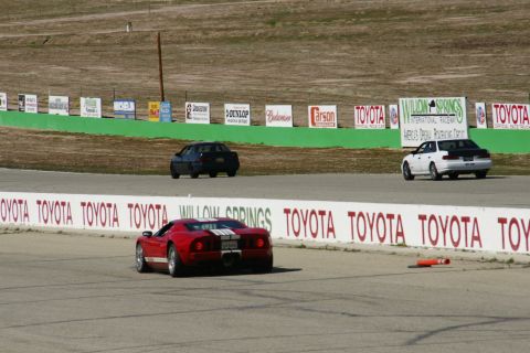 1995 Ford Taurus - Multiple vehicles race on a track with sponsor signage in the background.