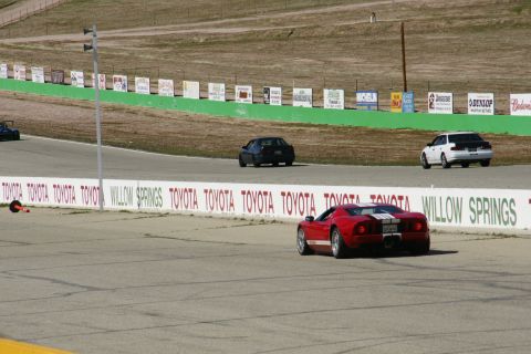 1995 Ford Taurus - Cars on a race track at Willow Springs, with sponsor signage along the barrier.