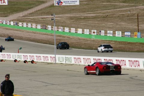 1995 Ford Taurus - A red sports car navigates a race track alongside other vehicles.