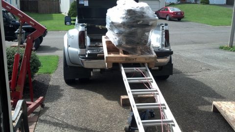 2008 Jeep Wrangler - A pickup truck is positioned to load an engine onto a pallet using a ramp and engine hoist.