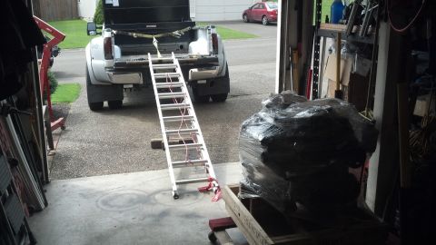 2008 Jeep Wrangler - A ramp is set up to load or unload an item from the bed of a pickup truck parked in a garage.