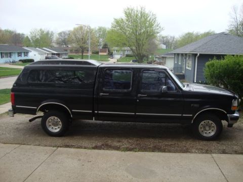 1999 Ford Ranger - Side view of a black crew cab pickup truck with a camper shell.