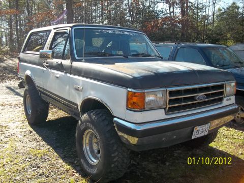 1989 Ford Bronco - A lifted 1987 Ford Bronco is shown from a three-quarter front view, parked next to another vehicle.