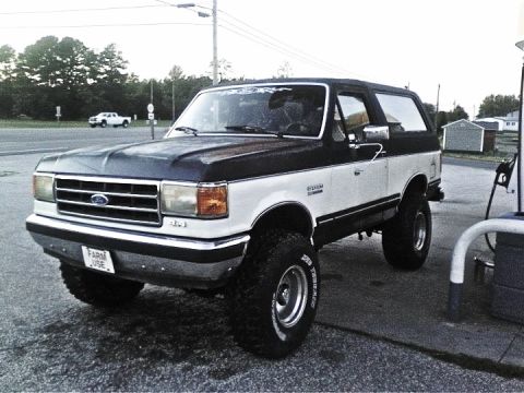 1989 Ford Bronco - This lifted Ford Bronco is parked at a gas station, possibly getting refueled.