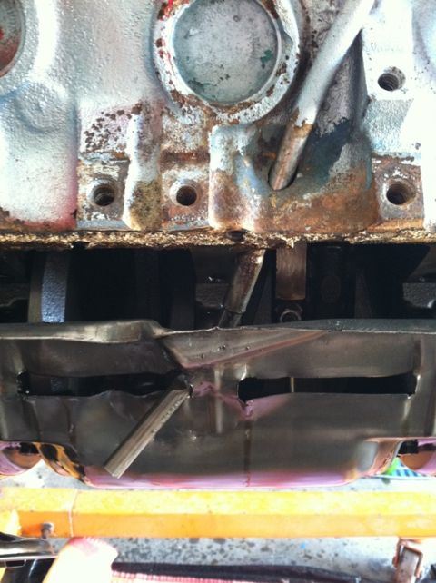 1967 Pontiac Grand Prix - Close-up view of a damaged engine oil pan and internal components.