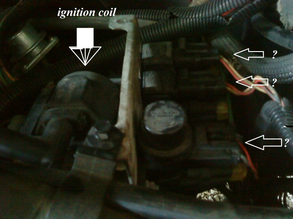 Engine compartment with ignition coil labeled. Wires and fuse box visible