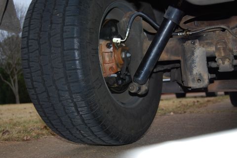 1975 Ford Ranchero - Close-up view of a vehicle's rear disk brake assembly, shock absorber, and tire.