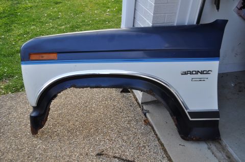 1986 Ford Bronco - A blue and white Ford Bronco fender, likely from a 1986 model, is shown removed from the vehicle.