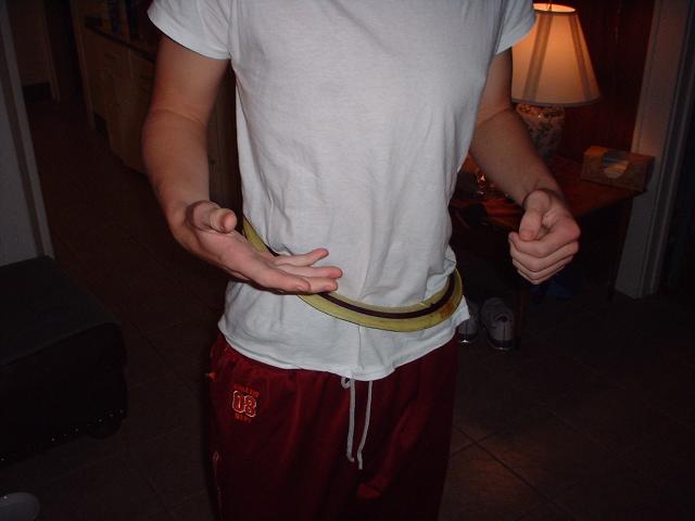 person in white t-shirt and red pants, holding a belt around their waist