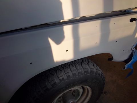 1978 Ford F-250 - This image shows the side panel of a truck, with a wheel visible. The panel appears to be in a state of repair or preparation for painting.
