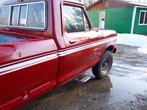 1978 Ford F-250 - A red pickup truck with a dent in the rear fender sits in a muddy lot with melting snow.